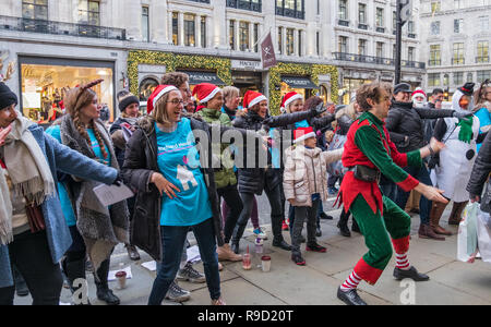 Hamleys' Elf Mike Rogers danze improvvisate con volontari da Londra i bambini ospizio Richard House, su Regent Street. Londra. Natale 2018 Foto Stock