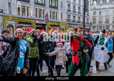 Hamleys' Elf Mike Rogers danze improvvisate con volontari da Londra i bambini ospizio Richard House, su Regent Street. Londra. Natale 2018 Foto Stock