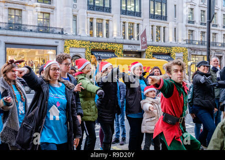 Hamleys' Elf Mike Rogers danze improvvisate con volontari da Londra i bambini ospizio Richard House, su Regent Street. Londra. Natale 2018 Foto Stock