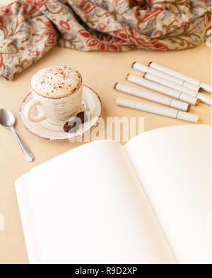Aprire lo schizzo prenota, mazzo di marcatori artistico e Latte su un tavolo. Orientamento verticale Foto Stock