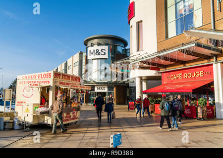 Westwood Cross Shopping Centre, Inghilterra. Super sabato. M&S store e Cafe Rouge ingresso con ciambella in stallo. Persone in cappotti. L'inverno. Sunshine. Foto Stock