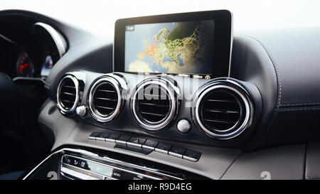 Vista dall'interno di un automobile su una parte del cruscotto con una unità di navigazione e sfocata street nella parte anteriore di una macchina Foto Stock