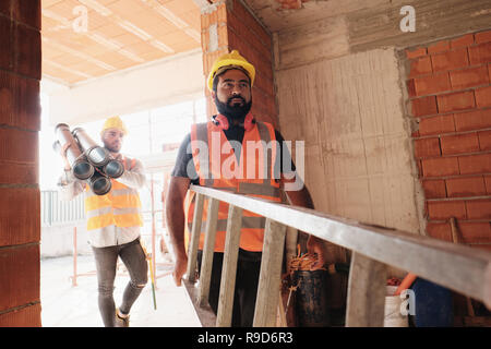 Lavoratori in cantiere utilizzando strumenti e attrezzature pesanti Foto Stock