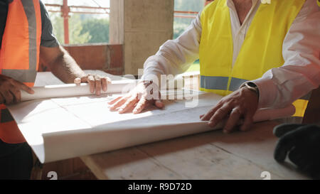 Il supervisore che mostra i piani di costruzione per i lavoratori nella nuova casa Foto Stock