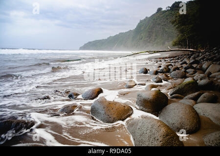 Onde che si infrangono sulle rocce sulla spiaggia nella valle Waipio sulla Big Island delle Hawaii. Foto Stock