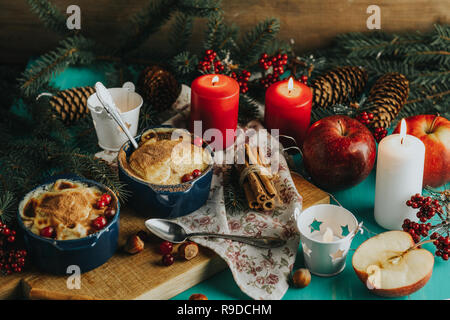Natale e Anno Nuovo composizione con dolce di mele deliziosi dessert, rami di abete rosso, posate su blu turchese tavolo in legno superficie, copia spice, H Foto Stock