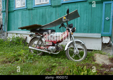 Kovrov, Russia. Il 3 settembre 2016. Motociclo Irbis manifattura cinese di chiusura permanente dalla pioggia di tavole di legno vicino alla vecchia casa in legno in co Foto Stock