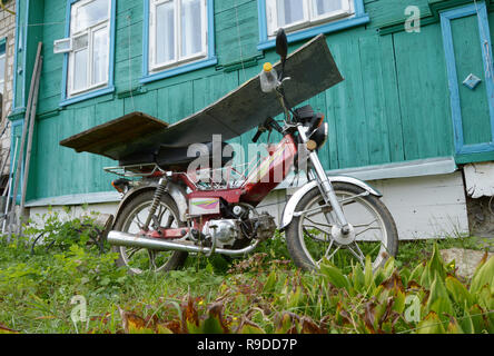 Kovrov, Russia. Il 3 settembre 2016. Motociclo Irbis manifattura cinese di chiusura permanente dalla pioggia di tavole di legno vicino alla vecchia casa in legno in co Foto Stock