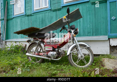 Kovrov, Russia. Il 3 settembre 2016. Motociclo Irbis manifattura cinese di chiusura permanente dalla pioggia di tavole di legno vicino alla vecchia casa in legno in co Foto Stock