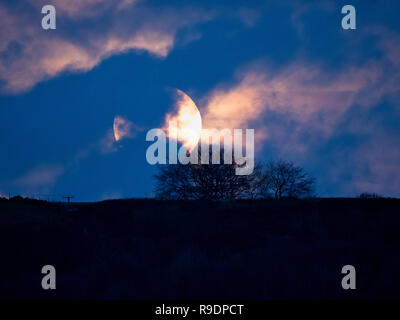 Wirksworth, UK. 22 Dic, 2018. Regno Unito: Meteo solstizio d'inverno Full Moon Rising in tra le nuvole sopra Cromford Moor, Bolehill preso dal StarDisc sopra Wirksworth nel Derbyshire Dales Credito: Doug Blane/Alamy Live News Foto Stock