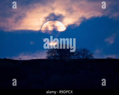 Wirksworth, UK. 22 Dic, 2018. Regno Unito: Meteo solstizio d'inverno Full Moon Rising in tra le nuvole sopra Cromford Moor, Bolehill preso dal StarDisc sopra Wirksworth nel Derbyshire Dales Credito: Doug Blane/Alamy Live News Foto Stock