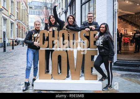 Londra, Regno Unito. Il 23 dicembre 2018. Il personale presso il pop-up store pongono con il "Scegli l'amore" segno al di fuori del negozio. sono tutti volontari - essi "Scegli l'amore" Natale pop-up shop appena fuori della Londra Carnaby Street nel quartiere di Soho, organizzata dalla carità aiutare i rifugiati, non Natale ruggenti scambi di doni e di elementi in aiuto dei profughi che hanno bisogno di aiuto. Credito: Imageplotter News e sport/Alamy Live News Foto Stock