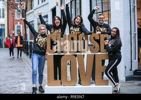 Londra, Regno Unito. Il 23 dicembre 2018. Il personale presso il pop-up store pongono con il "Scegli l'amore" segno al di fuori del negozio. sono tutti volontari - essi "Scegli l'amore" Natale pop-up shop appena fuori della Londra Carnaby Street nel quartiere di Soho, organizzata dalla carità aiutare i rifugiati, non Natale ruggenti scambi di doni e di elementi in aiuto dei profughi che hanno bisogno di aiuto. Credito: Imageplotter News e sport/Alamy Live News Foto Stock