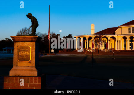 Pinehurst, North Carolina, Stati Uniti d'America. 23 Dic, 2018. Dicembre 23, 2018 - PINEHURST, N.C., STATI UNITI D'AMERICA - Il gibbous calante luna tramonta dietro il putter Boy statua, un simbolo iconico di Pinehurst Resort e il club house. Il dicembre luna piena, che si è verificato a Dic. 22, è spesso chiamato la piena luna fredda secondo il vecchio contadino dell'Almanacco del. È l'ultima luna piena per il 2018. Questo caso celesti ha coinciso un giorno dopo il Solstizio d'inverno. L'abbinamento di questi due eventi un giorno al di là non si verificherà di nuovo fino al 2029. Credito: Timothy L. Hale/ZUMA filo/Alamy Live News Foto Stock