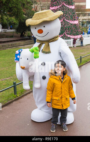 Bournemouth, Regno Unito. Il 23 dicembre 2018. Il pupazzo di neve e visita Snowdog Bournemouth, bella rinfrescata una grigia giornata drizzly come coda di bambini eccitato per avere le loro foto scattata con loro in Giardini inferiori di Bournemouth. Ragazzo pone con il pupazzo di neve. La struttura ad albero di Varsavia, parte del Bournemouth albero di Natale il paese delle meraviglie in background. Credito: Carolyn Jenkins/Alamy Live News Foto Stock