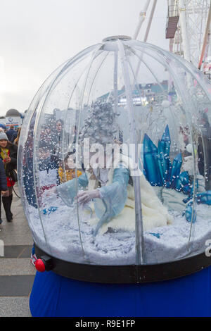 Bournemouth, Regno Unito. Il 23 dicembre 2018. I bambini sono affascinati dalle snowglobe umana con la bella regina delle nevi racchiusi nella sua neve blizzard, come ella graziosamente scivola lungo gli incantevoli visitatori giovani e vecchi. Credito: Carolyn Jenkins/Alamy Live News Foto Stock