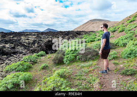 Un uomo che guarda al paesaggio vulcanico vicino alla strada turistica trail a vulcano Caldera Blanca, Lanzarote, Isole Canarie, Spagna Foto Stock