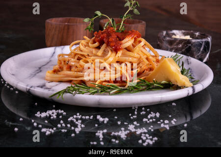 Delizioso spaghetti servito con il formaggio parmigiano reggiano su una lastra di marmo Foto Stock