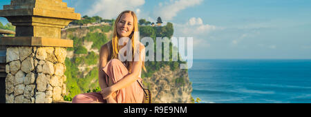 Giovane donna traveler in Pura Luhur Uluwatu temple, Bali, Indonesia. Un paesaggio fantastico - scogliera con il blu del cielo e del mare banner, formato lungo Foto Stock