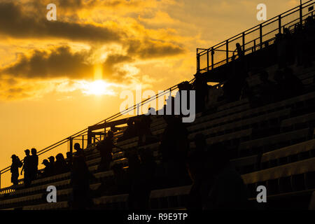 Persone sedute e in piedi sulle gradinate con GOLDEN SUNSET Foto Stock