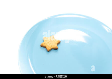 Piccola stella gingerbread Cometa di Natale sulla piastra di blu. Coda di cometa fatta con effetto di illuminazione riflessa sulla piastra. Foto Stock