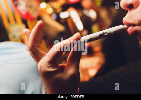 Calore IQOS-non-burn prodotto del tabacco tecnologia. Uomo con e-sigaretta nella sua mano prima di fumare. Foto Stock