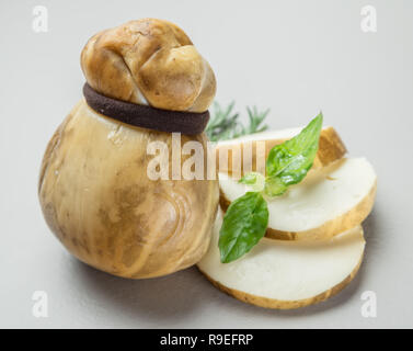 Italiano tradizionale di scamorza affumicata formaggi alle erbe su sfondo grigio. Foto Stock