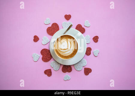 Fragranti deliziosi cappuccini su un sfondo di festa con molti cuori. Concetto per il giorno di San Valentino o il giorno della donna. Foto Stock