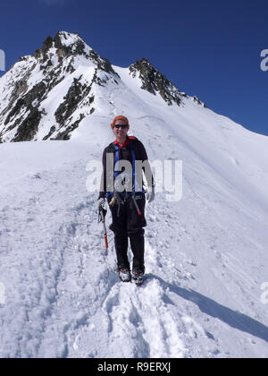 Scalatore femmina escursionismo in giù su un ghiacciaio da un elevato picco di montagna Foto Stock