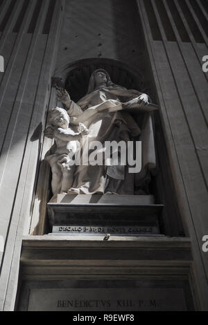 Statua religiosa di una donna e di cherubini nella chiesa, con la luce che cade su di esso Foto Stock