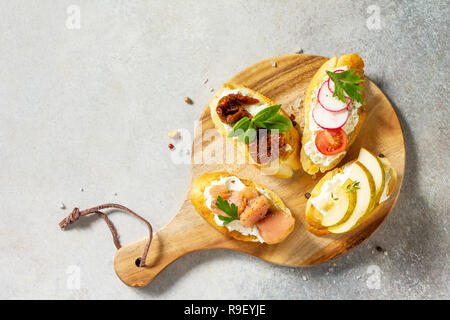 Antipasti italiani spuntini impostato per il vino. Spaghetti con formaggio a pasta morbida, pera, Rafano, salmone e pomodori secchi su una pietra di luce sullo sfondo. Vista superiore piatta Foto Stock