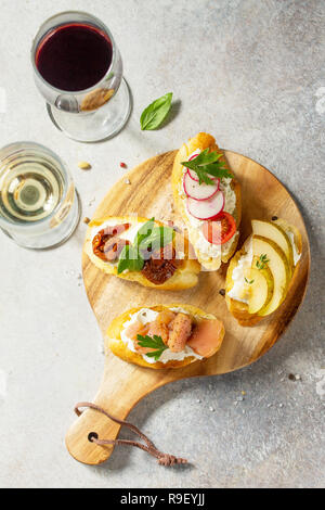Antipasti italiani spuntini impostato per il vino. Spaghetti con formaggio a pasta morbida, pera, Rafano, salmone e pomodori secchi su una pietra di luce sullo sfondo. Vista superiore piatta Foto Stock