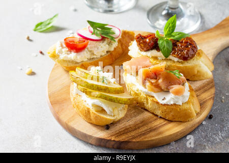 Antipasti italiani spuntini impostato per il vino. Spaghetti con formaggio a pasta morbida, pera, Rafano, salmone e pomodori secchi su una pietra di luce sullo sfondo. Foto Stock