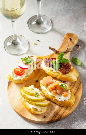 Antipasti italiani spuntini impostato per il vino. Spaghetti con formaggio a pasta morbida, pera, Rafano, salmone e pomodori secchi su una pietra di luce sullo sfondo. Foto Stock