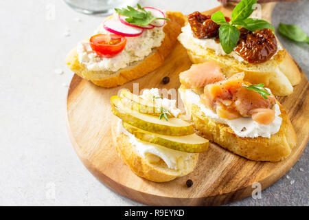 Antipasti italiani set snack close-up per il vino. Spaghetti con formaggio a pasta morbida, pera, Rafano, salmone e pomodori secchi su una pietra di luce sullo sfondo. Foto Stock