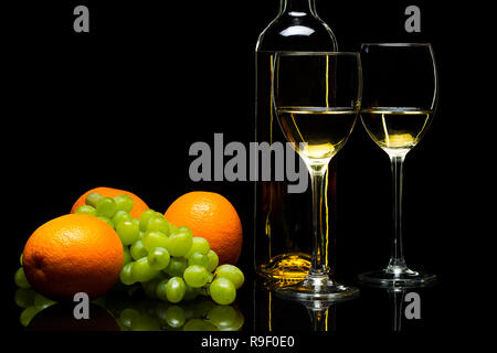 Tre Bicchieri per il vino, un grappolo di uva e arance su uno sfondo nero, studio luce Foto Stock