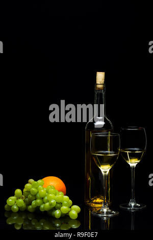 Tre Bicchieri per il vino, un grappolo di uva e arance su uno sfondo nero, studio luce Foto Stock