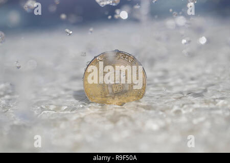 Bitcoin cryptocurrency moneta fisica posto sul lato della piscina dove acqua sguazzare Foto Stock