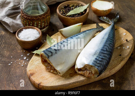 Pesce fresco. Ingredienti per la cottura del pesce per la marinata. Sgombri con sale e spezie su di un tavolo di legno. Foto Stock