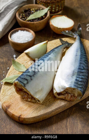 Pesce fresco. Ingredienti per la cottura del pesce per la marinata. Sgombri con sale e spezie su di un tavolo di legno. Foto Stock