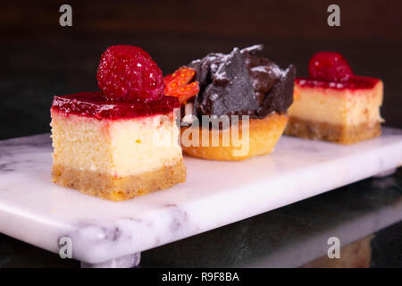 Serie di mini torte in assortimento su piastra bianca. Il menu del ristorante. Blackberry torta con lamponi. Tartlet con frutti. Close up. Foto Stock