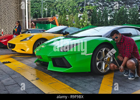 Un turista indiano prende un selfie davanti a una Lamborghini Aventador e altre vetture di lusso parcheggiato presso il Marina Bay Sands Hotel, Marina Bay, Singapore Foto Stock