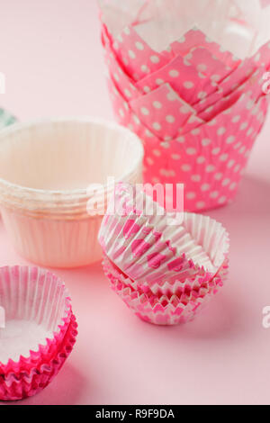 Tortina casi torre in una varietà di colori e dimensioni sulla tavola rosa pronto per la celebrazione di vacanza, il concetto di cottura. Carta caso di cottura per cupcake muffin e Foto Stock