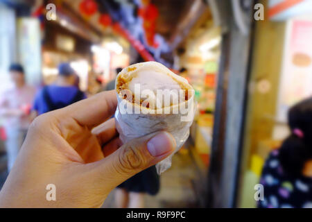 Mano che tiene il rullo di arachidi gelati e dessert di Jin Feng, Ruifang, Taiwan. Foto Stock