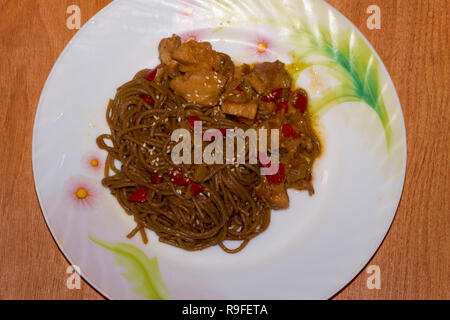 Piastra con yakisoba su sfondo di legno Foto Stock