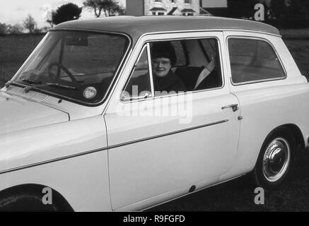 Anni sessanta, storico, una donna seduta sul sedile del passeggero di una a 3 porte Austin A40 Farina auto parcheggiate fuori con la finestra aperta. Questa piccola famiglia auto berlina è stato identificato come una Austin A40 Farina per distinguerlo da un precedente40 e modelli è stato fabbricato tra il 1958 -1967. Foto Stock