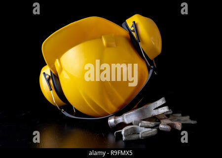 Chiave di officina e casco su una tavola nera. Accessori per Officina dei lavoratori. Sfondo scuro. Foto Stock