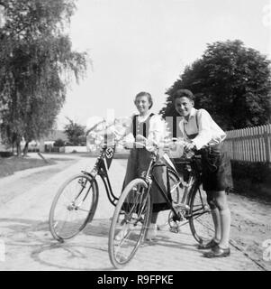 Due adolescenti mostrare con orgoglio le bandiere nazionali sulle loro moto in pre-guerra in Germania, ca. 1935. Foto Stock