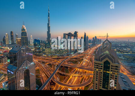 Paesaggio urbano in vista di Burj Khalifa e complesso interscambio autostradale e grattacieli lungo la Sheikh Zayed road in serata a Dubai, Emirati Arabi Uniti, Foto Stock