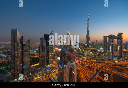 Paesaggio urbano in vista di Burj Khalifa e complesso interscambio autostradale e grattacieli lungo la Sheikh Zayed road in serata a Dubai, Emirati Arabi Uniti, Foto Stock